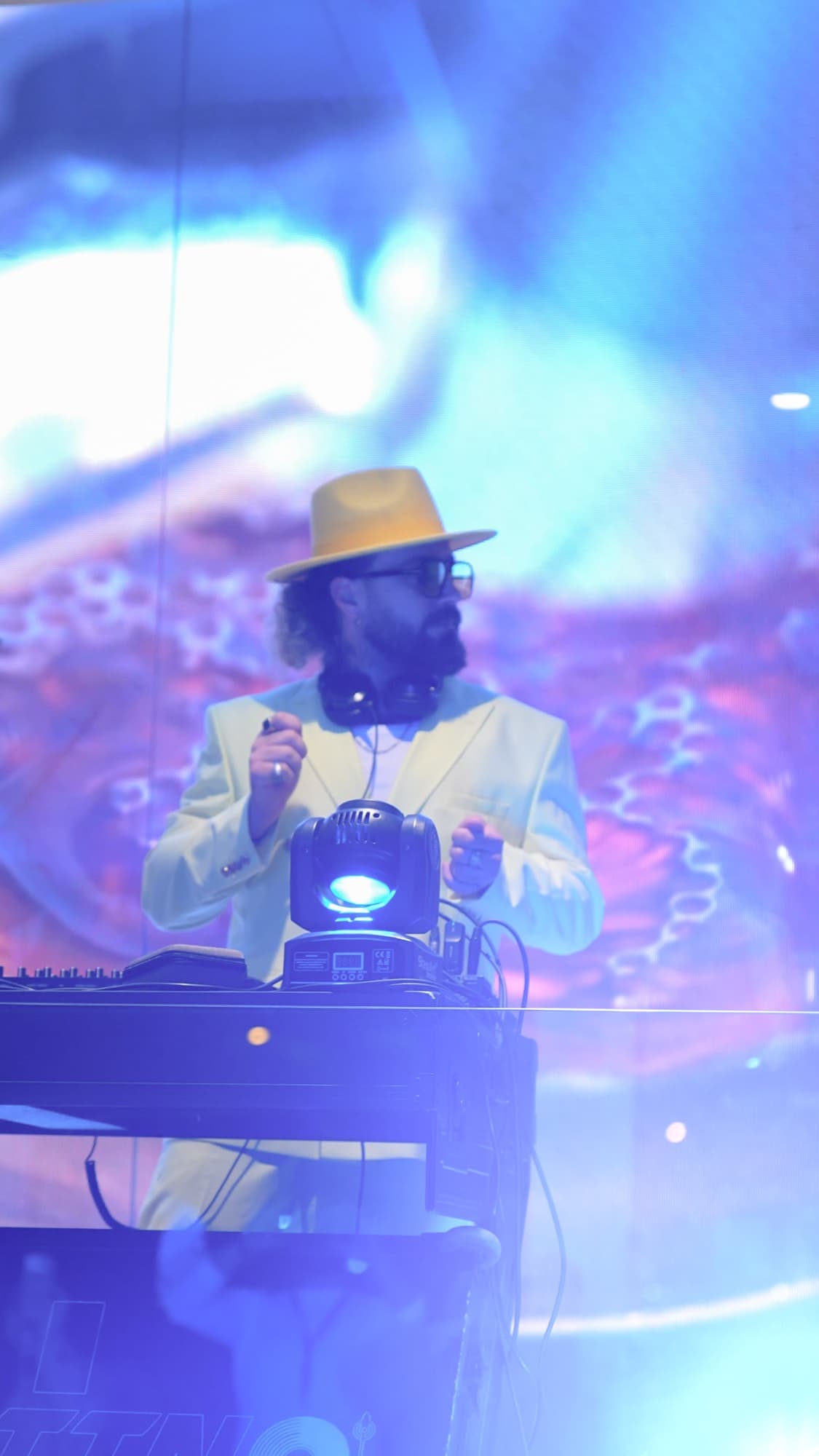 Sarı şapkalı bir DJ, mavi ve mor sahne ışıkları altında performans sırasında